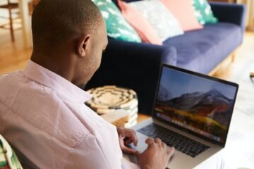 black man freelancing on laptop in cozy room